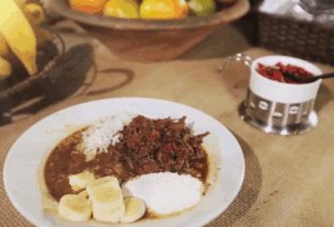 Prato típico barreado servido em panela de barro com arroz branco e banana-da-terra ao lado.